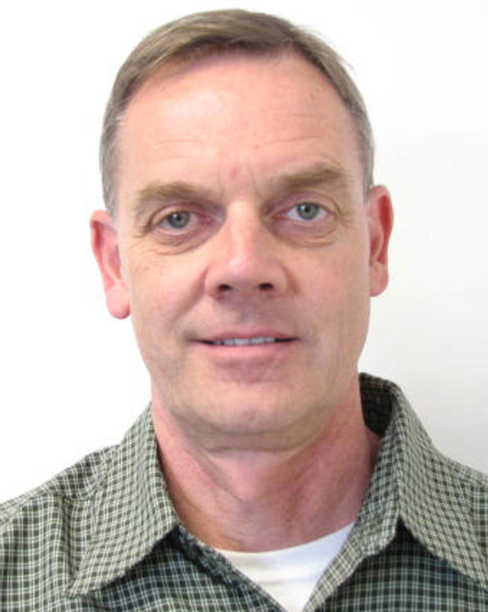 Fred Lindberg with short light hair, green checked shirt, light grey background