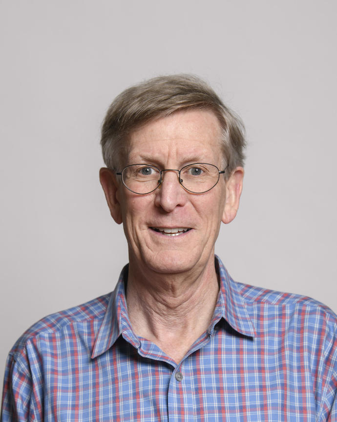 George Lauder with short gray hair wearing glasses and a plaid shirt in front of grey background