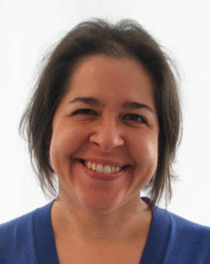 Julie Knippa Colby smiling, with medium-length dark hair, blue sweater, white background