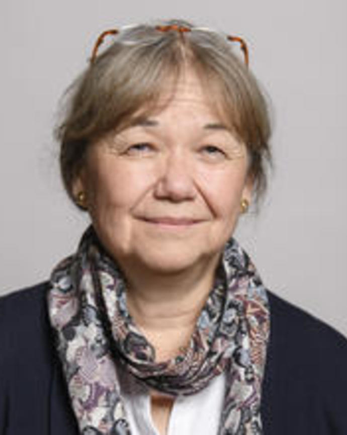 Naomi Pierce with long grey hair pulled back, glasses on head, dark sweater, light shirt, and colorful scarf