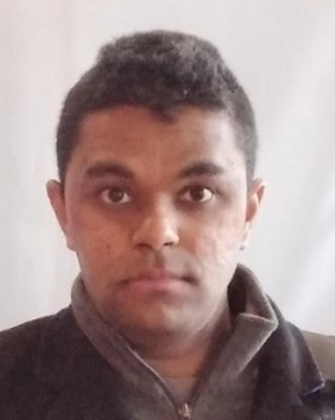 Vikram Chandra with short dark hair, grey fleece, and white background