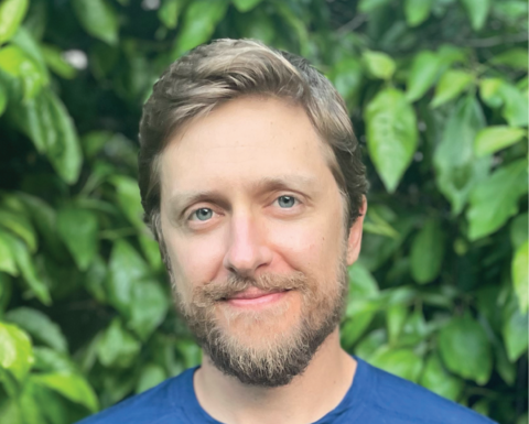 Man in a blue shirt in front of leaves