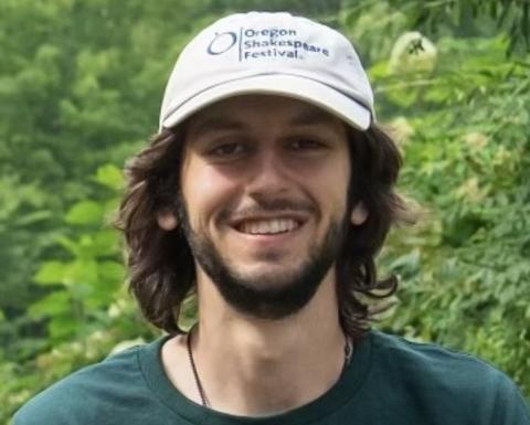 Graduate student Nikhil Chari outside wearing a hat, beard and smiling