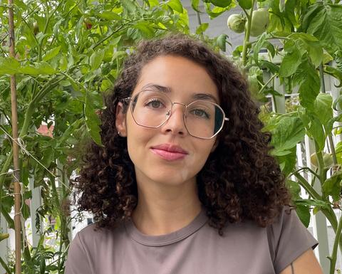 woman wearing glasses and brown shirt standing in front of plants