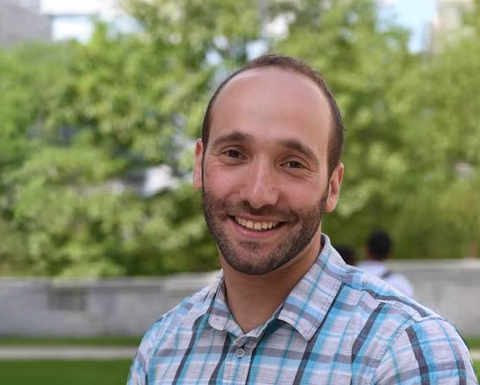 Man with a beard wearing a plaid shirt standing outside